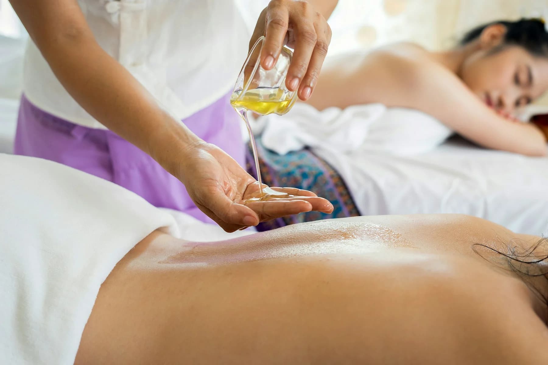 Massage oil prepared beside clients resting on treatment tables
